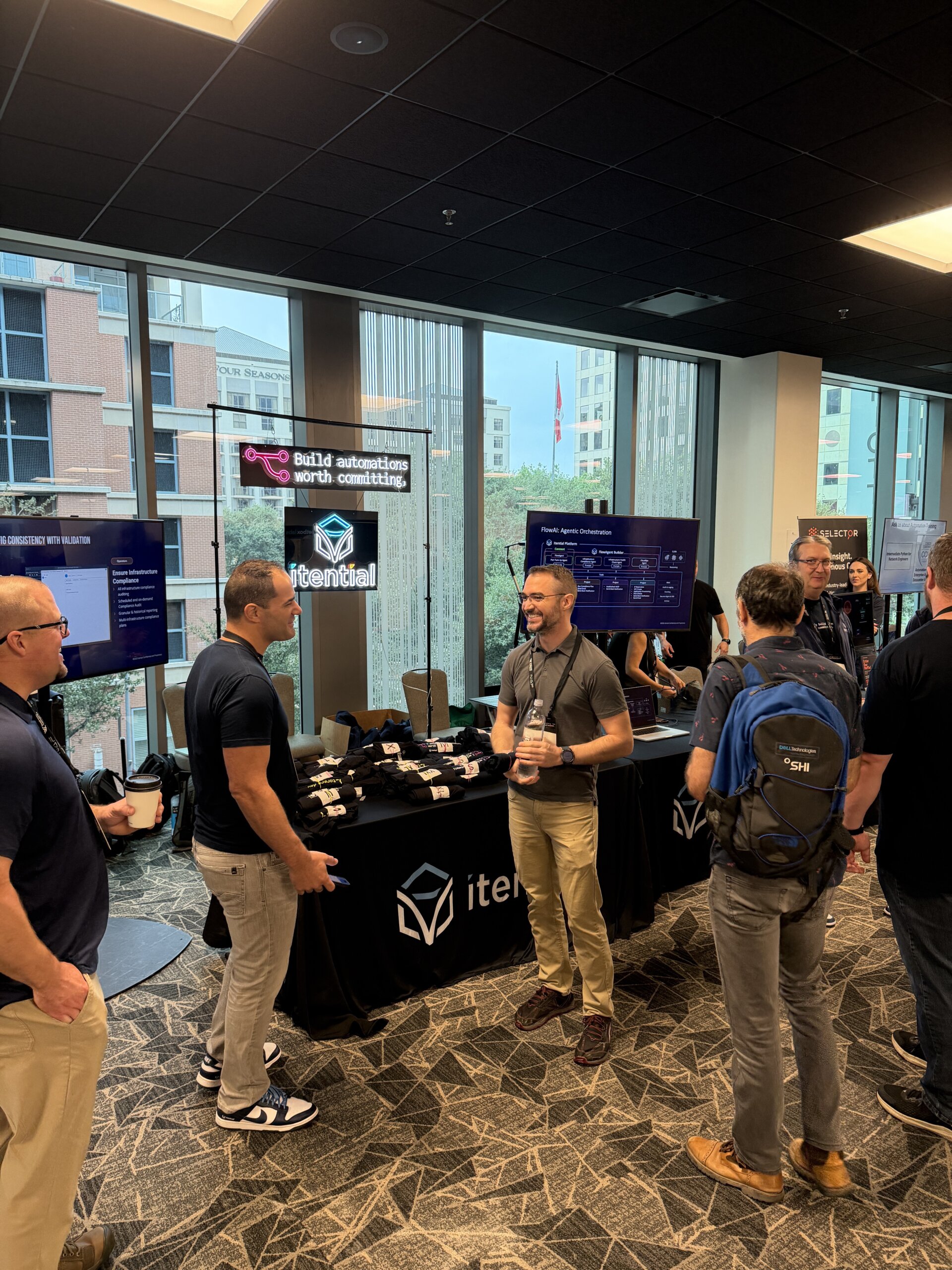 itential team at booth at autocon 4 with only build automations worth committing neon sign